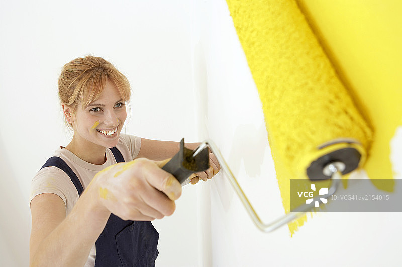 年轻女人粉刷白色墙壁图片素材