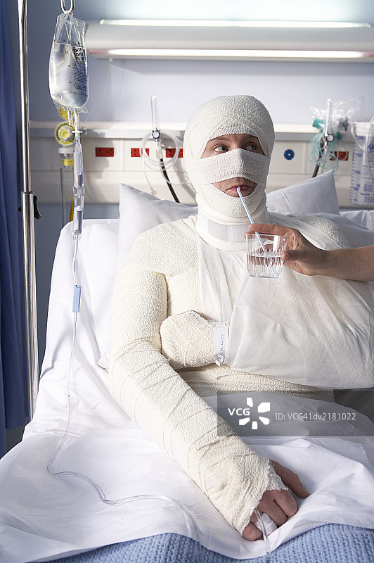 身上缠着绷带用吸管喝水的男人图片素材