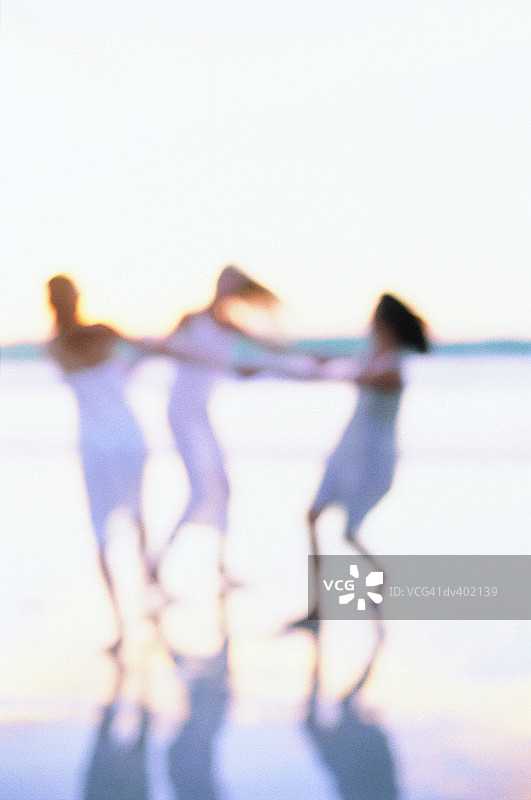 三个女人在海滩上围成一圈跳舞图片素材