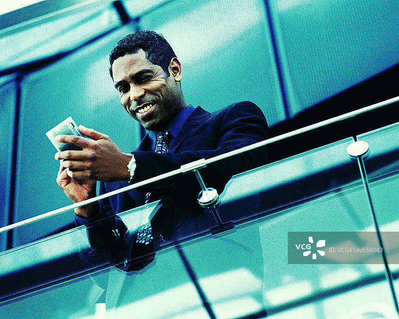 站在阳台上使用掌上电脑的商人图片素材