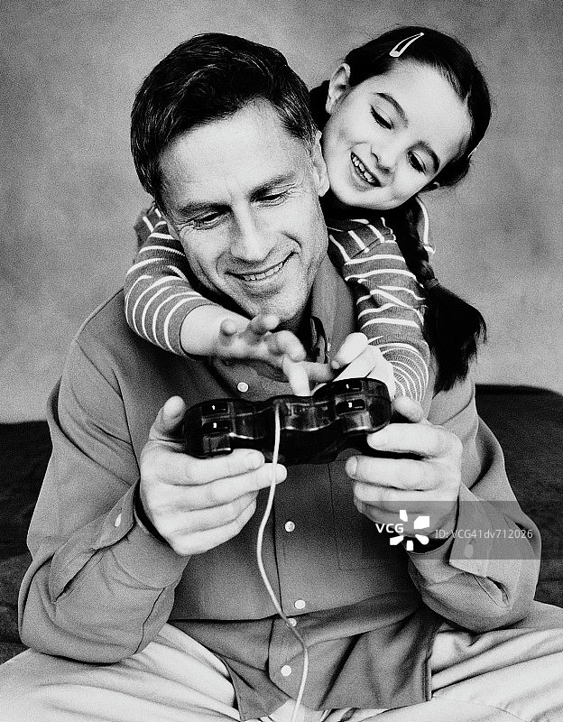 女孩越过父亲玩电脑游戏图片素材