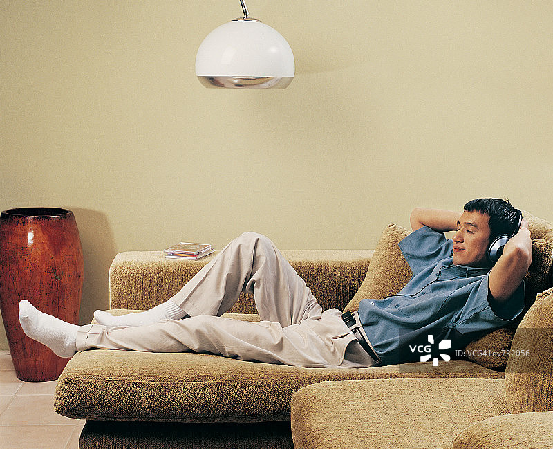 戴着耳机躺在沙发上闭着眼睛的男人图片素材