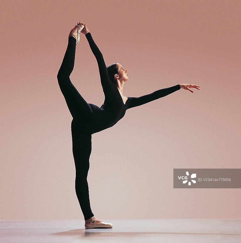 单腿站立并抬起脚的西班牙裔女舞者图片素材