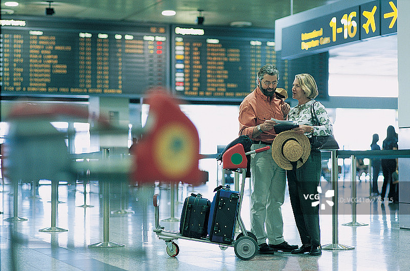 在机场到达出发指示牌前男人给女人票图片素材