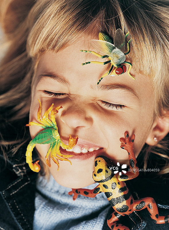 脸上带着玩具青蛙、玩具蝎子和玩具苍蝇的男孩肖像图片素材