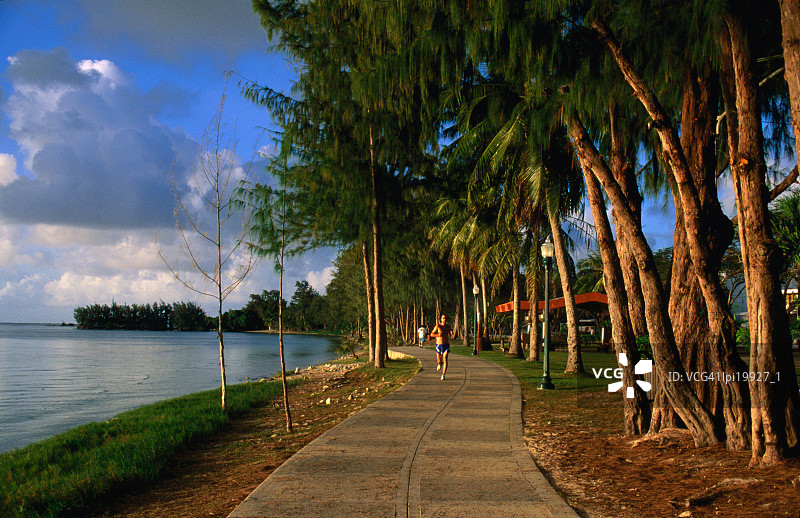 北马里亚纳群岛加拉班海滩路公园小径上的慢跑者图片素材