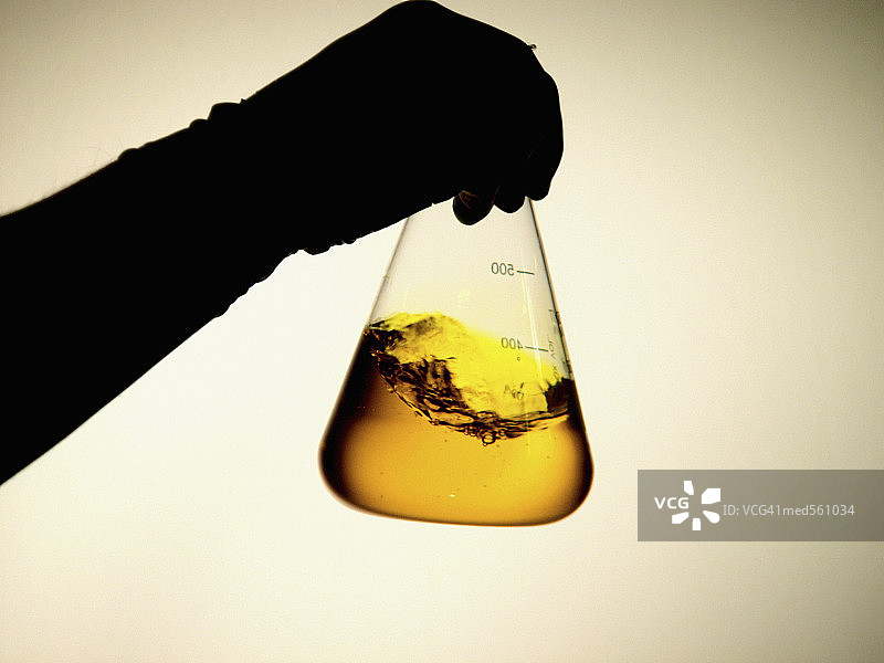 手持黄色液体测量烧杯特写图片素材