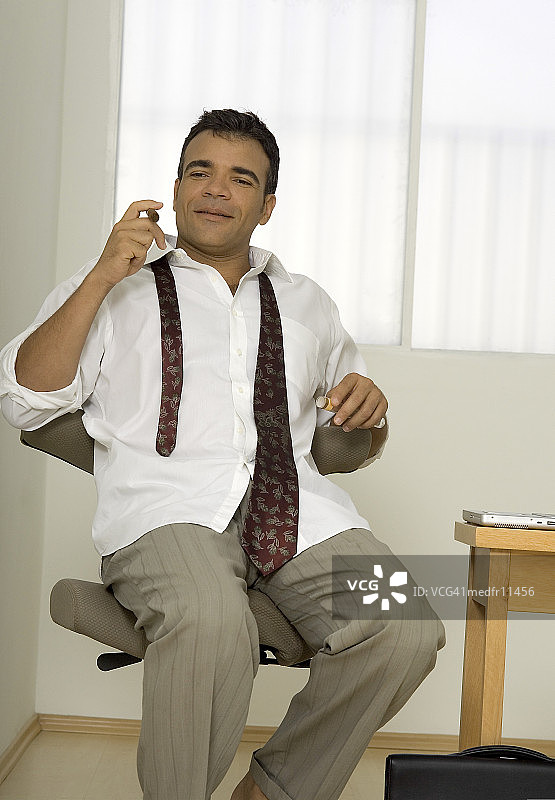 男人坐在椅子上，领带松开图片素材