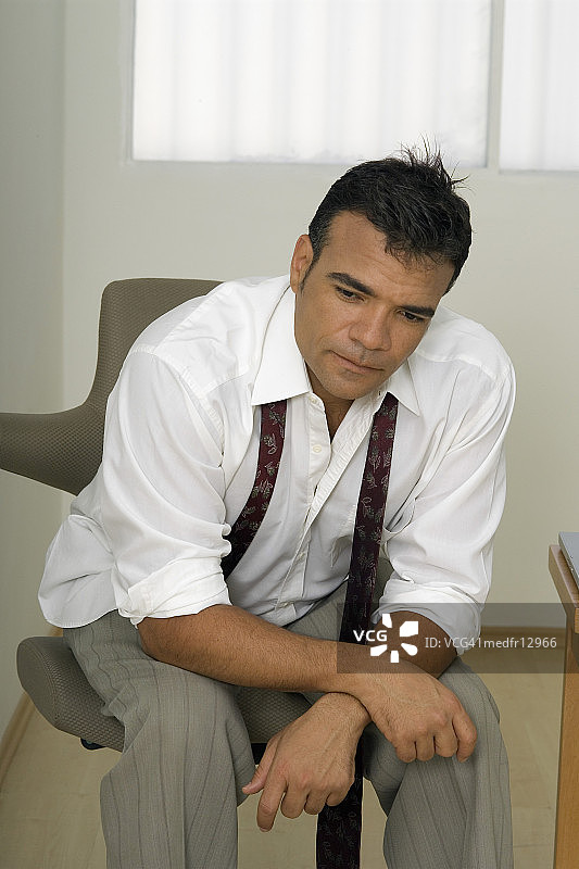 坐在椅子上，领带松开的商人图片素材