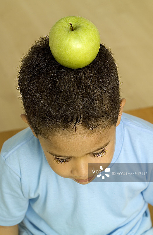 头顶苹果的男孩，特写图片素材