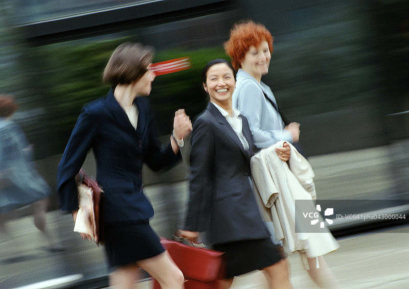 三位女商人在街上行走，微笑，模糊图片素材