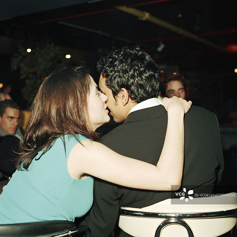 年轻女子亲吻年轻男子的脸颊，后视图图片素材