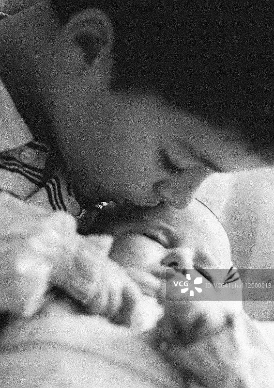男孩亲吻婴儿，黑白特写图片素材