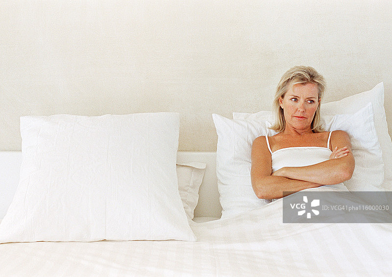 手臂交叉放在胸前躺在床上的女人图片素材