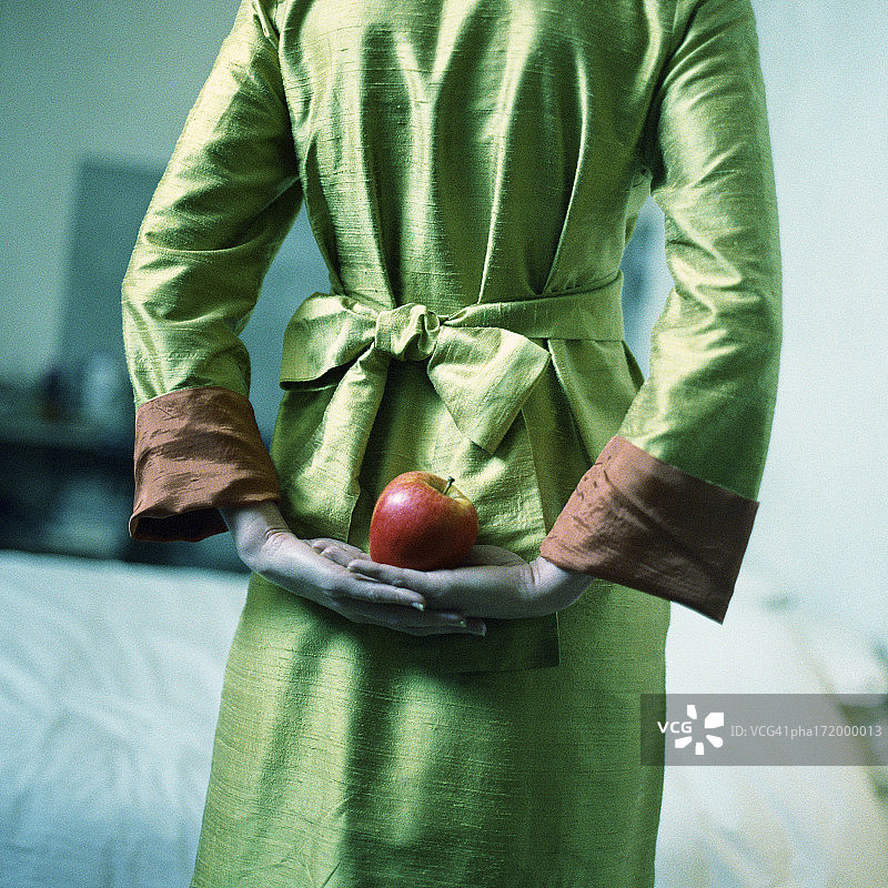 拿着藏在身后的苹果的女人，中段，后视图图片素材
