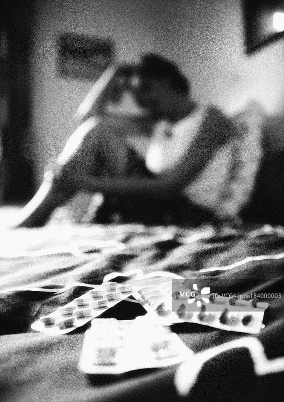 坐在床上的男人，前景是平板电脑，模糊的黑白照片图片素材