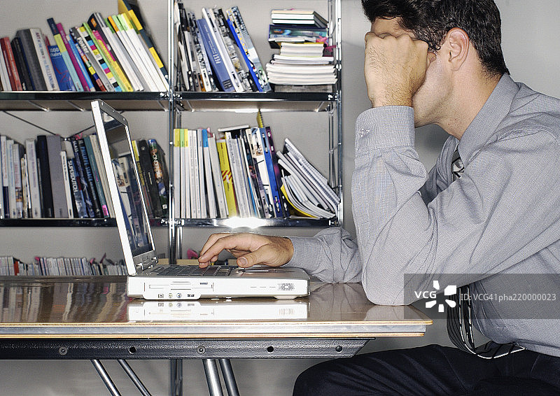 男人在办公室使用笔记本电脑，侧视图图片素材