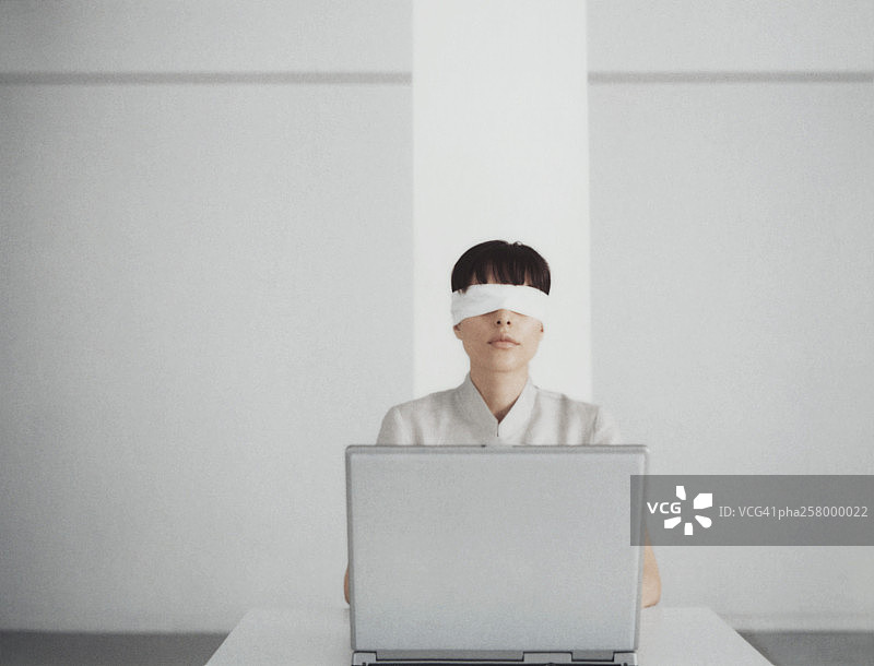蒙着眼睛坐在笔记本电脑后面的女人图片素材