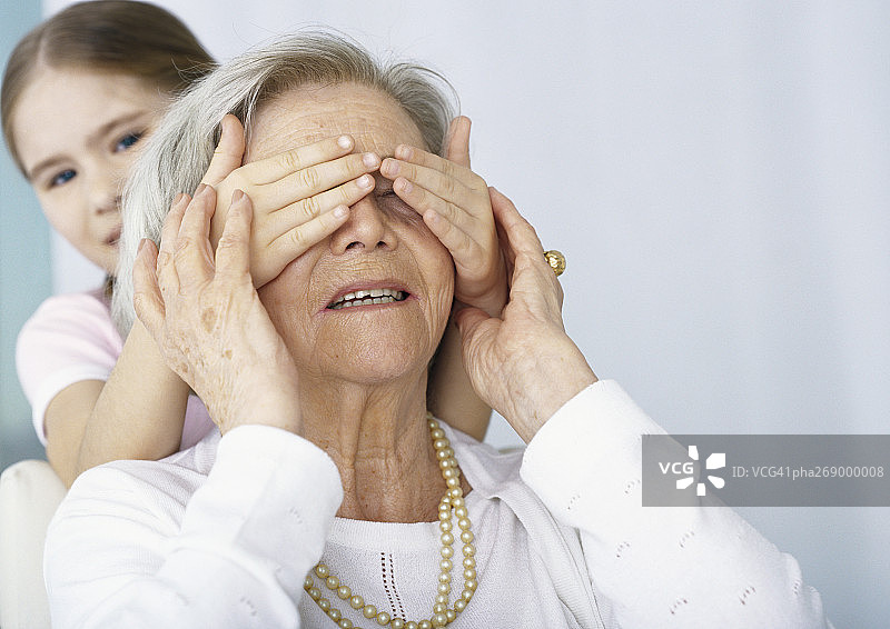 女孩从背后蒙住祖母的眼睛图片素材