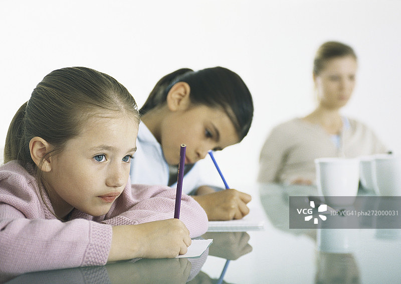两个女孩在桌旁写作，背景是妇女图片素材