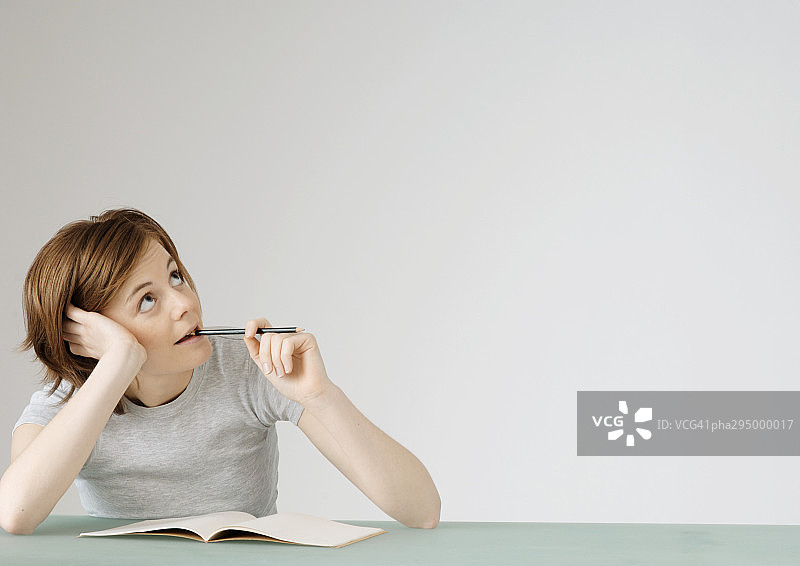 年轻女人拿着铅笔，坐在打开的笔记本前图片素材