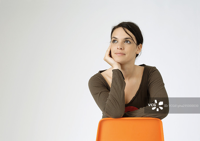 年轻女人反向坐在椅子上，肖像图片素材