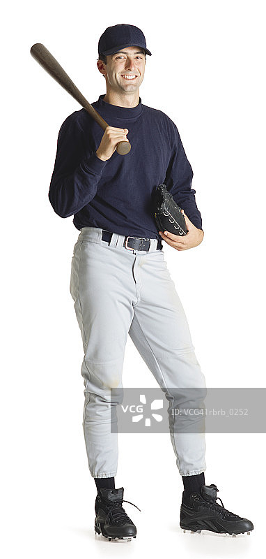 戴着帽子，身穿蓝色衬衫的年轻白人棒球运动员肩扛球棒，面带微笑图片素材
