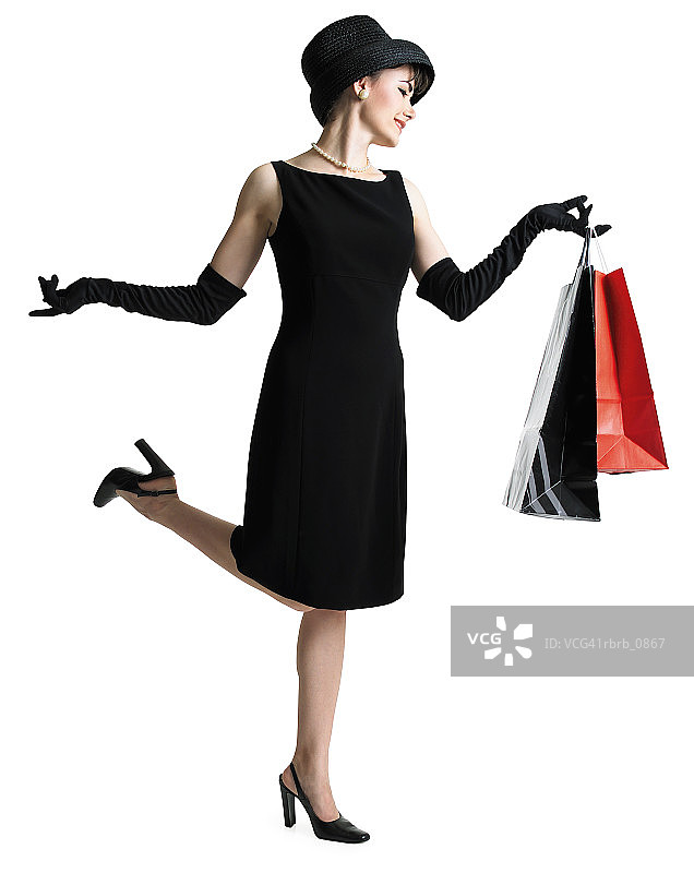 穿着黑色连衣裙戴着帽子的精致女人拿着购物袋踢起她的脚的剪影图片素材