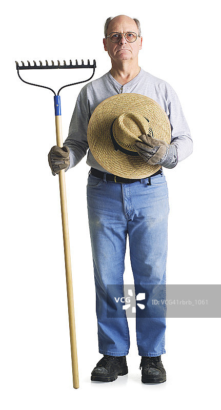 戴着帽子和耙子的老年男性农民严厉地盯着镜头图片素材