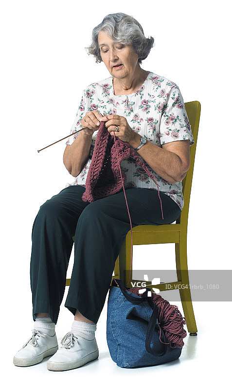 坐在椅子上缝纫和编织的年长的白人祖母图片素材