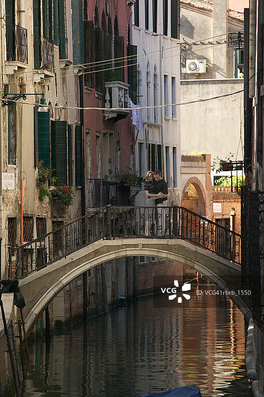 在威尼斯度假时，一对年轻漂亮的白人情侣在桥上深情相拥图片素材