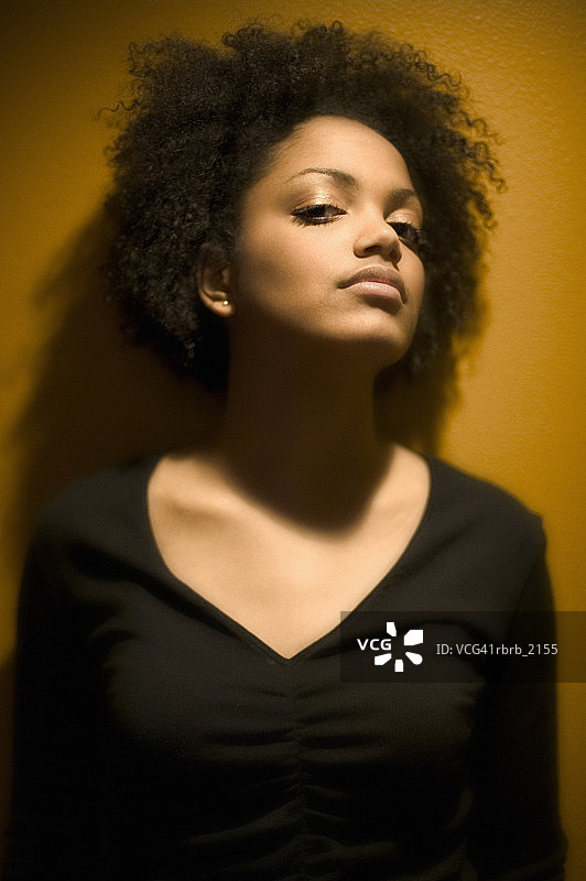 一位身穿黑色毛衣的年轻成年女性的半身特写，表情严肃图片素材