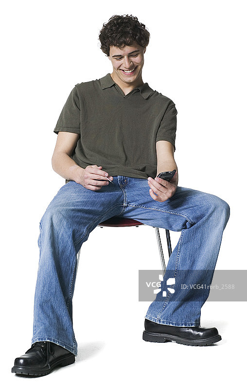 生活方式画像：一位年轻成年男子坐在椅子上使用掌上电脑图片素材