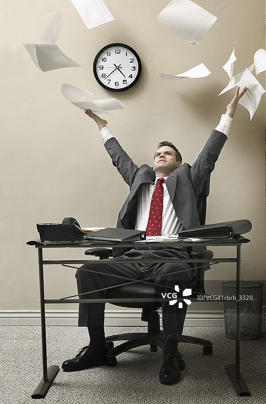 坐在办公桌后向上抛纸的商人图片素材