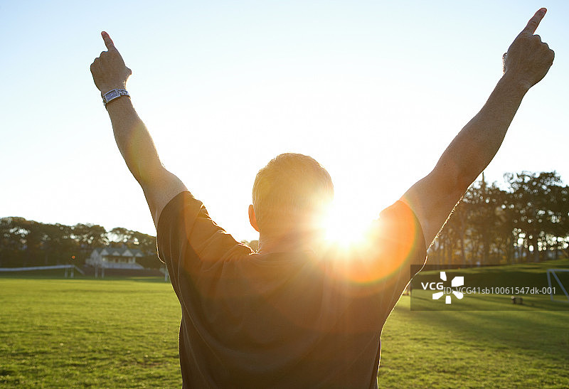 公园里的男人张开双臂迎接阳光，后视图图片素材