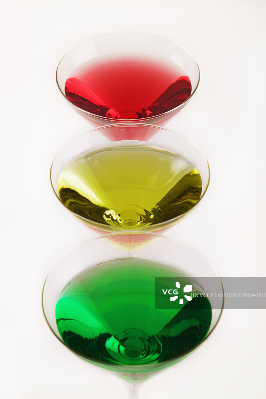 三个盛有彩色液体的马提尼酒杯，白色背景，工作室拍摄图片素材