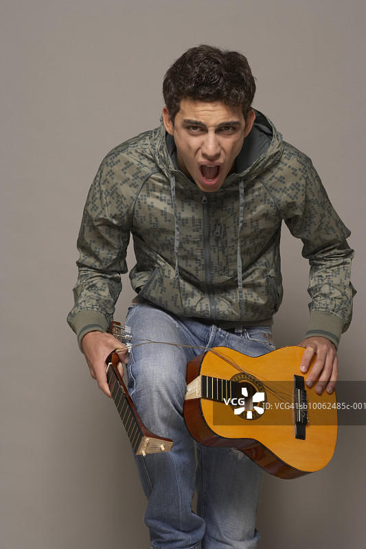 年轻男子摔吉他并大喊，肖像图片素材