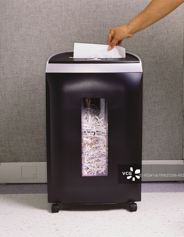 手将纸张放入碎纸机图片素材