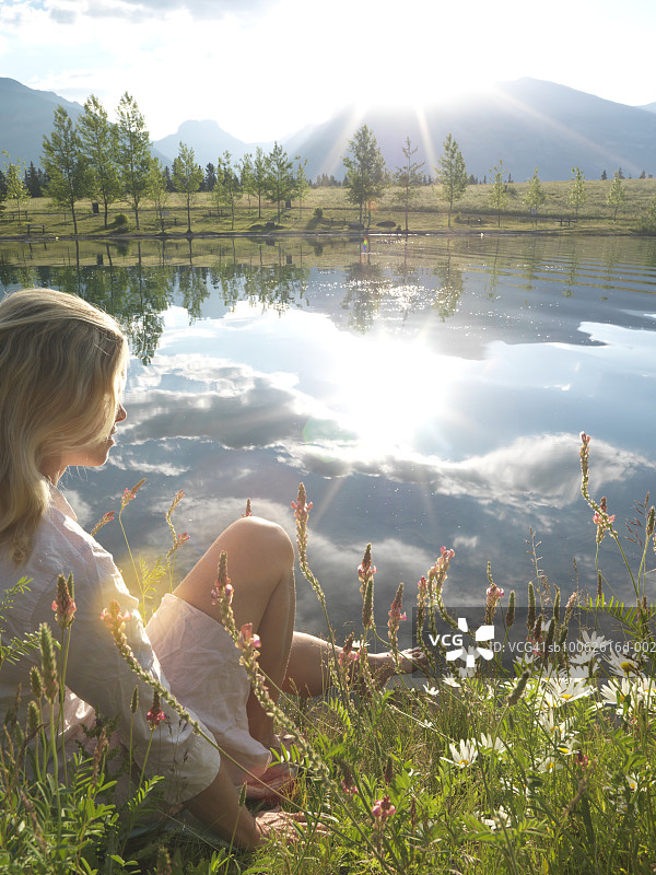 坐在山间湖畔草地上的女人图片素材