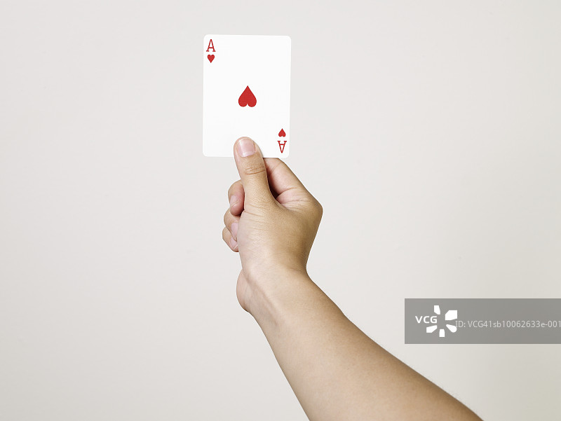 年轻女子拿着红桃A纸牌，手臂和手部特写，工作室拍摄图片素材