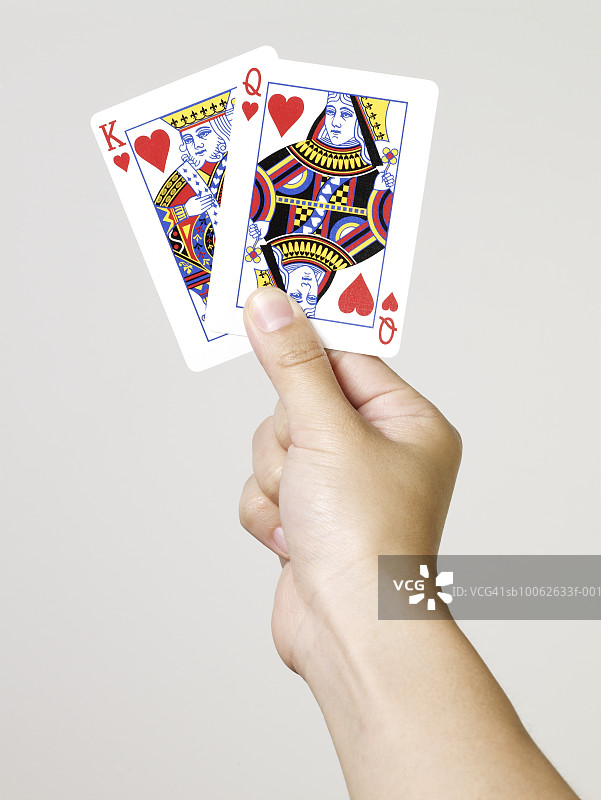 年轻女人手持红桃国王和王后扑克牌特写图片素材