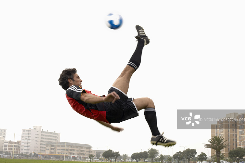 男人在半空中踢足球，侧视图图片素材