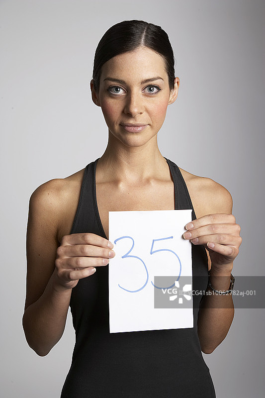 年轻女人拿着带有数字35的盘子，肖像图片素材