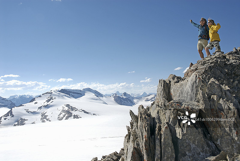 父亲和儿子(13-14岁)站在山顶，举起手臂图片素材
