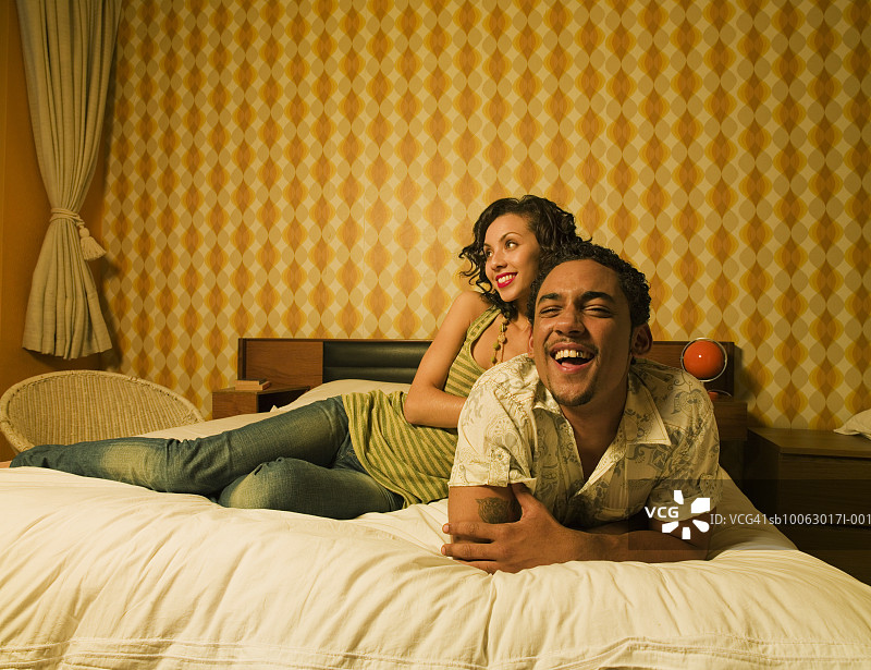 年轻夫妇在床上放松，男人看着镜头图片素材