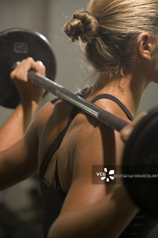 年轻女人用杠铃锻炼，后视图图片素材