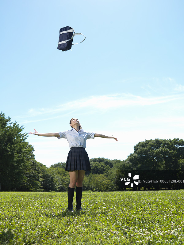 张开双臂，把书包扔向空中的青少年女学生图片素材