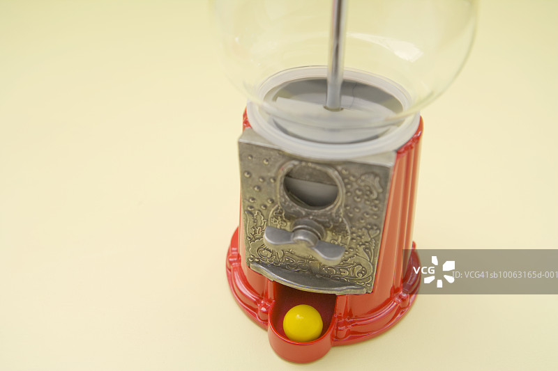 从空红色泡泡糖机里取出的一颗黄色泡泡糖图片素材