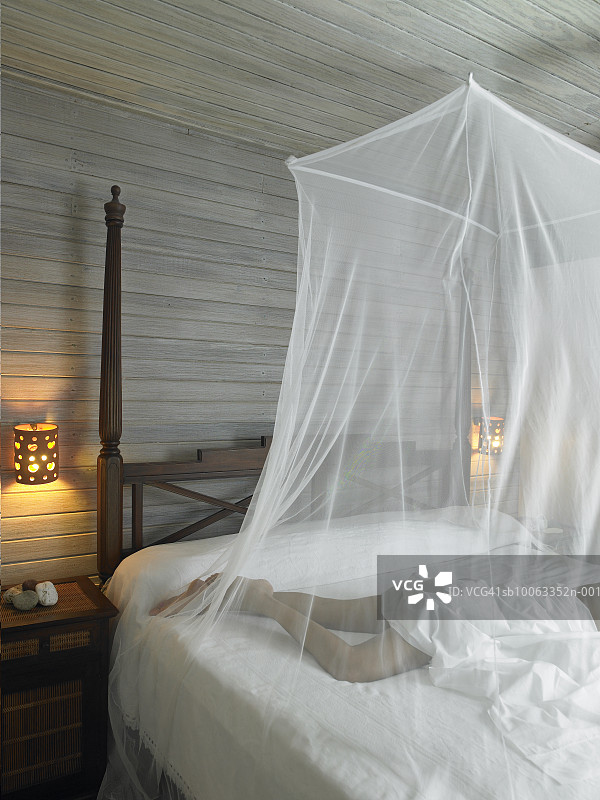 女子躺在有蚊帐的床上，下半身图片素材