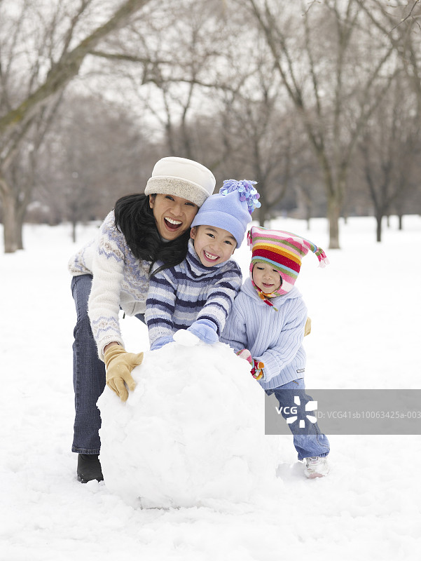 母亲和孩子们(4-9岁)在雪地里玩耍，微笑图片素材